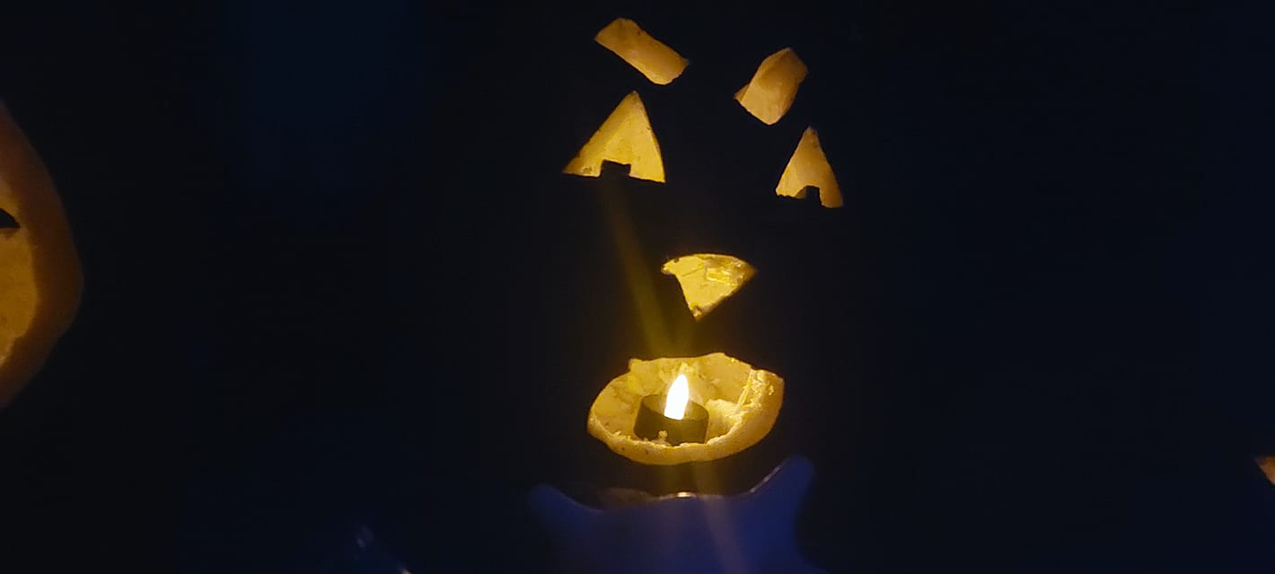 A lit jack-o-lanturn with a shocked face carved on it sits in the dark